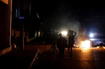 Un grupo de personas pasa junto a la basura prendida fuego en medio de una calle durante una protesta contra los frecuentes cortes de electricidad en Cuba (REUTERS/Norlys Pérez)