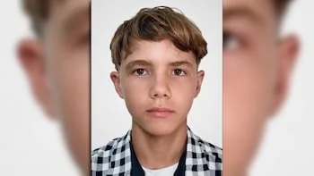 Primer plano de un joven caucásico con cabello castaño y corto, ojos marrones, y una camisa de cuadros azul y blanco, mirando al frente